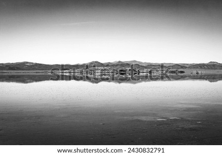 Classic black and white art landscape of Mono Lake reflections of the surrounding desert landscape and clear cloudless sky in the eastern Sierra Nevada desert of California, USA.