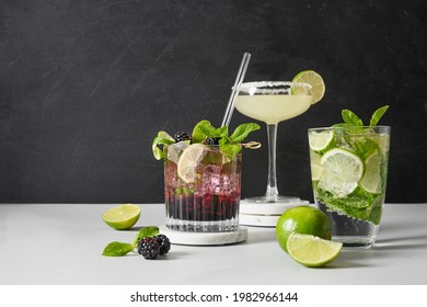 Classic And Blackberry Mojito Cocktails With Lime On Black And White Background In Modern Style. Three Summer Freshness Beverage For Festive Party. Summer Holiday Mocktail. Copy Space.