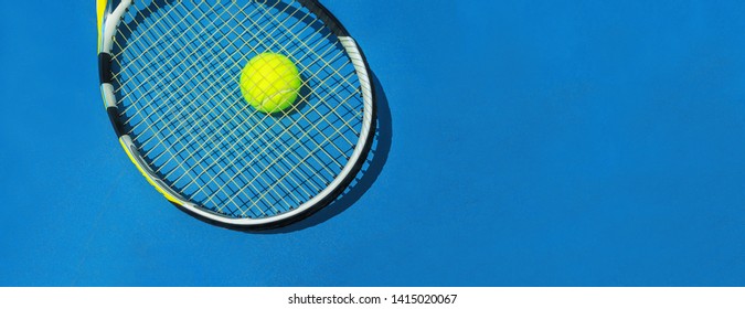 Classic Blue color of the 2020 year. Summer sport concept with tennis ball and racket on blue hard tennis court. Flat lay, top view, copy space. Blue and yellow.
