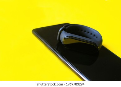 Classic blue fitness bracelet with smartphone for sports training on bright background. Selective focus.