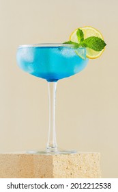 Classic  Blue Lagoon Cocktail With Lemon On Modern Still Life On Podium On Beige Background With Shadow. Festive Party. Summer Holiday Mocktail. Vertical