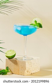 Classic  Blue Lagoon Cocktail With Lime On Modern Still Life On Podium On Beige Background With Shadow. Festive Party. Summer Holiday Mocktail. Vertical