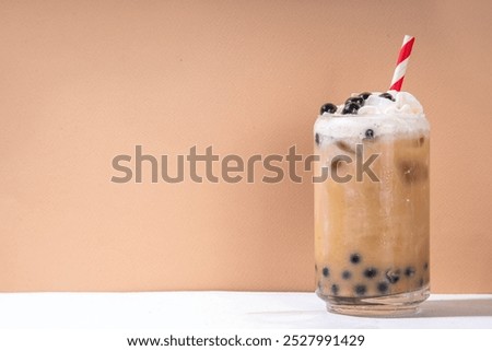 Classic boba bubble tea with tapioca pearls and whipped non-dairy creamer on top of glass, summer cold sweet dessert drink on white table background copy space