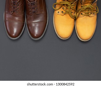 Classic brown leather men's shoes and Yellow men's work boots from natural nubuck on gray black background top view flat lay copy space. Fashion male concept, genuine leather shoes, sale, shop. - Shutterstock ID 1300842592