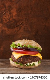 Classic Burger With Beef Meat, Melted Cheese, Salat, Tomato, Onion, And Bun With Sesame On Wooden Background. 