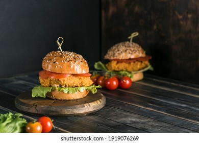 Classic Burger with chicken in a bun with sesame tomatoes, lettuce and mustard sauce. Dark background with copy space. Horizontal orientation. Fast food, takeaway