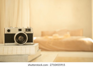 A classic camera rests on a stack of books in a cozy bedroom