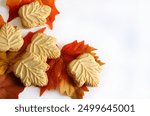 Classic Canadian maple leaf shaped cookies and maple leaves on background. Maple cream sandwiched between two crunchy cookies isolated on white background. Copy space.