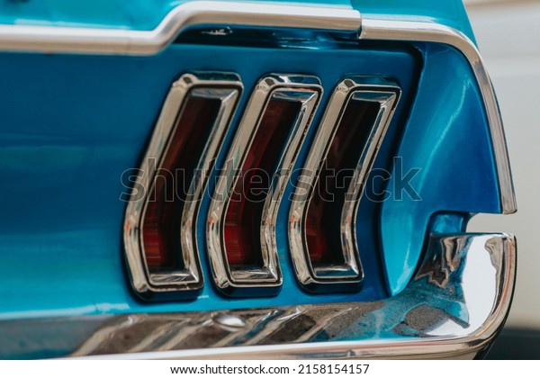 Classic car\
background. Close-up of the tail light and bumper of classic\
design, selective background. The concept of restoring old cars.\
Retro car blue color selective\
background.