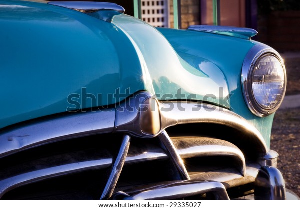 Classic car restoration detail in sunset. Nice\
Chrome bumper.