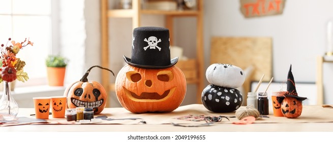 Classic Carven Spooky Jack-o-lantern With Big, Gape-toothed Grin In Pirate Hat Standing On Wooden Table With Different Handmade Halloween Decorations And Painted Pumpkins, No People