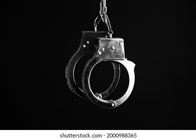 Classic chain handcuffs hanging on black background