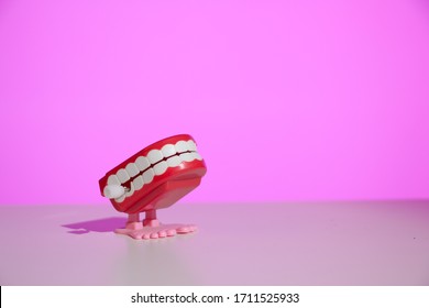 Classic chattering teeth wind-up toy on a modern pink background with copy space.