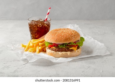 Classic cheeseburger, french fries and soda drink on gray background. BBQ grill menu.