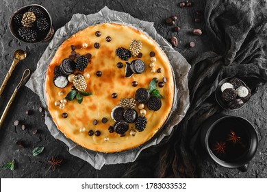 Classic Cheesecake With Caramel, Mini Oreos, Mint Leaves, And Berries On Paper Over Dark Background, Top View. Delecious Sweets And Dessert