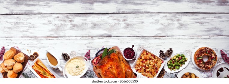 Classic Christmas turkey dinner. Above view bottom border on a white wood banner background. Turkey, potatoes and sides, dressing, fruit cake and plum pudding. - Powered by Shutterstock