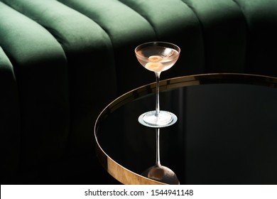 Classic cocktail glass on glass table in night club restaurant. Alcohol cocktail drink, close-up. Modern alcoholic beverage