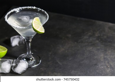 Classic cocktail of margarita with a salted rim and lime on a textured dark background, space for text - Shutterstock ID 745750432