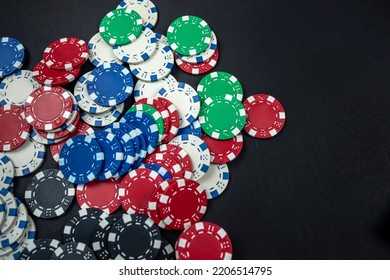 Classic Colored Round Poker Chips Scattered On A Black Table. Isolated Poker Concept. Gambling