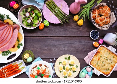 Classic Easter Ham Dinner. Overhead View Frame On A Dark Wood Background With Copy Space. Ham, Scalloped Potatoes, Vegetables, Eggs, Hot Cross Buns And Carrot Cake.