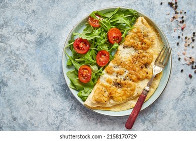 Classic egg omelette served with cherry tomato and arugula salad on side