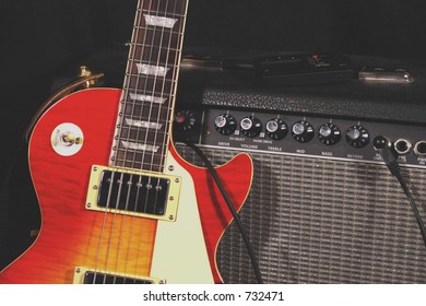 Classic Electric Guitar With Sunburst Pattern Leaning Against An Amplifier. Electronic Tuner On Top Of Amp.