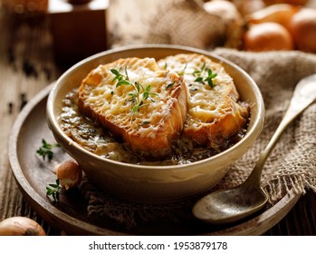 Classic French onion soup baked with cheese croutons sprinkled with fresh thyme, close up view.