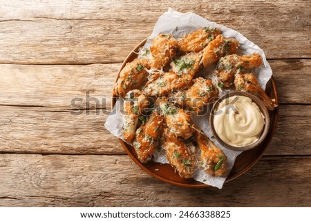 Classic Garlic Parmesan Butter Chicken Wings served with mayonnaise close-up in a plate on the table. Horizontal top view from above
