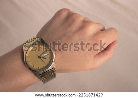Classic Gold Watch on wrist. Woman watching watch in wrist watch on a light background. First-person view (FPV), first-person point of view (POV)
