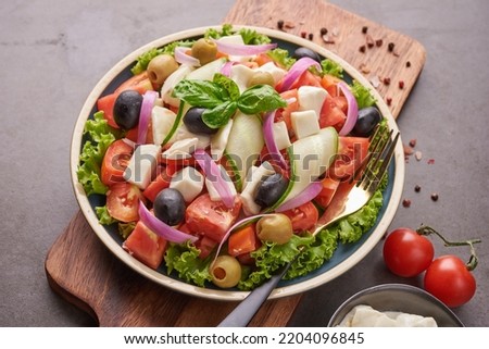Classic greek salad of fresh vegetables, cucumber, tomato, sweet pepper, lettuce, red onion, feta cheese and olives with olive oil. Healthy food, top view