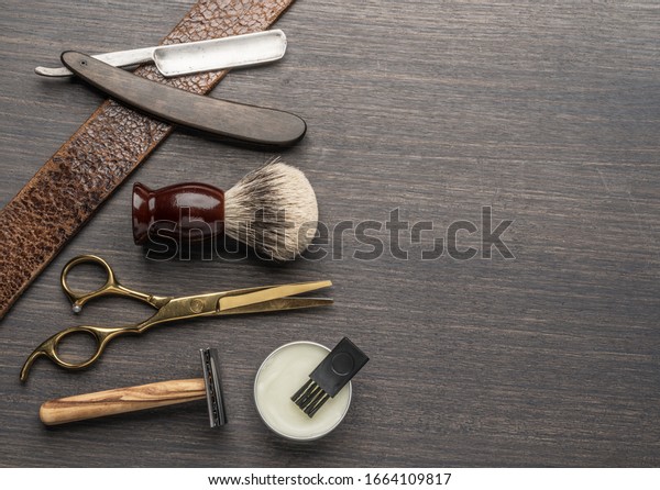 Classic grooming and hairdressing tools on wooden\
background. Top view on barbershop instruments  laying on dark\
wooden table.
