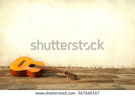 classic guitar lying in front of a wall as background