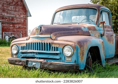 A classic half ton pickup truck in front of a red barn on the Saskatchewan prairies