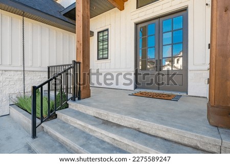 classic home exterior with cement tile patio deck stone entry wide front door patio with chairs and a fire pit area with trees and bbq seating dining on a bright sunny colorful day blue sky 