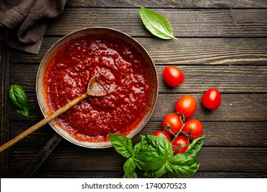 Clásica salsa de tomate italiana casera con albahaca para pasta y pizza en la sartén sobre fondo de madera, vista superior.