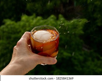 Classic Home-made Old Fashioned Alcohol Drink With Ice Ball And Orange Zest, Trees Sky And Rain Drops. Stay At Home Balcony Bad Weather Cocktail Party. Good For Website Blog Recipes Articles