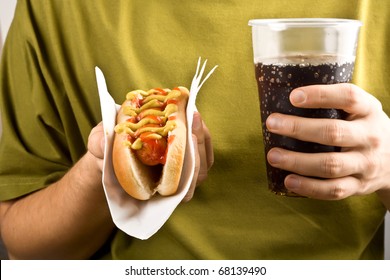 classic hot dog with mustard and ketchup and cola holding in hands