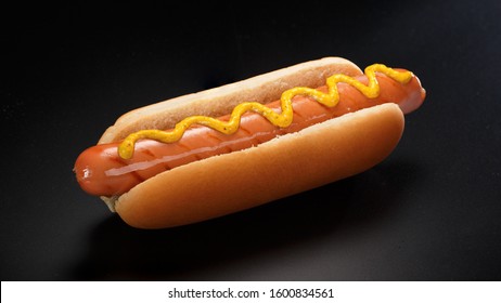 Classic Hot Dog With Mustard On A A Black Background.