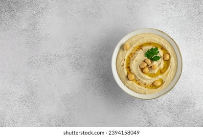 Classic hummus in a white plate on a gray background. Top view. Copy space. Arabic, Turkish cuisine