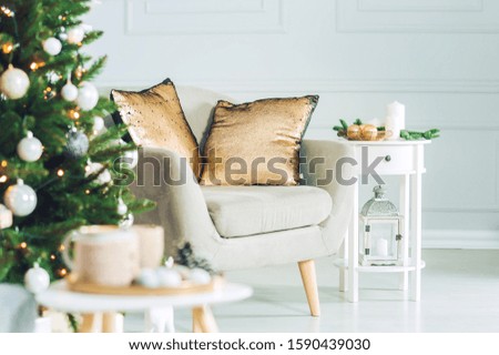 Classic interior, with an armchair, tables and a Christmas tree with decorations on a light wall background