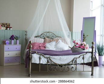Classic interior light bedroom with large bed and chest of drawers.