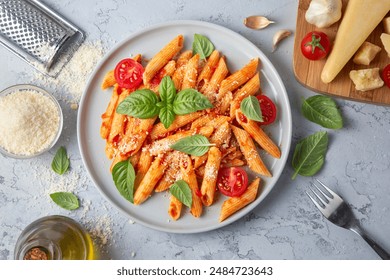 Classic italian pasta penne alla arrabiata with basil and freshly grated parmesan cheese on dark table. Penne pasta with chili sauce arrabbiata.