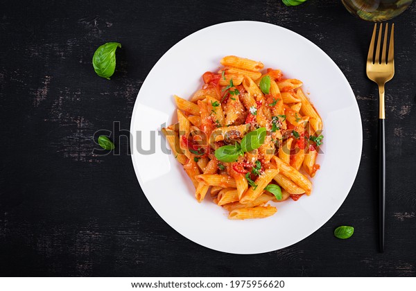 Classic italian\
pasta penne alla arrabiata with basil and freshly grated parmesan\
cheese on dark table. Penne pasta with chili sauce arrabbiata. Top\
view, above, copy space