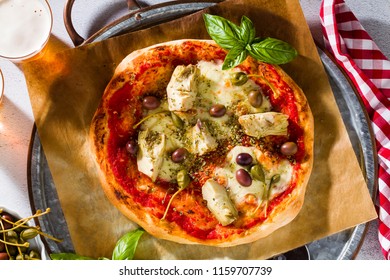 Classic Italian Pizza Margherita with artichokes, olives and capers on a table with beer and a knife. Banner for restaurants, advertising. - Powered by Shutterstock
