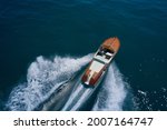 Classic Italian wooden boat fast moving aerial view. Top view of a wooden powerful motor boat. Luxurious wooden boat fast movement on dark water.