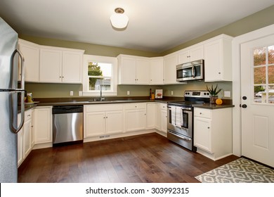 Classic Kitchen With Green Interior Paint, Hardwood Floor, And White Cabinets.