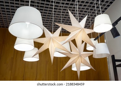Classic lampshades and lamps in the form of stars under the lattice ceiling of the shopping center. Many lamps with fabric lampshades