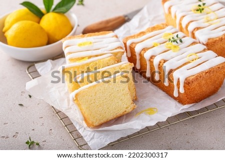 Classic lemon pound cake with powdered sugar glaze sliced on parchment paper topped with lemon zest