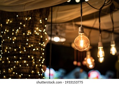 Classic lighting bulb in orange warm light shade during it glowing with blurred of other bulbs as bokeh background. Object for interior decoration, selective focus photo. - Powered by Shutterstock