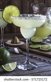 Classic Lime Margarita Cocktails With Pitcher, Limes Slices Sitting On Rustic Wooden Table